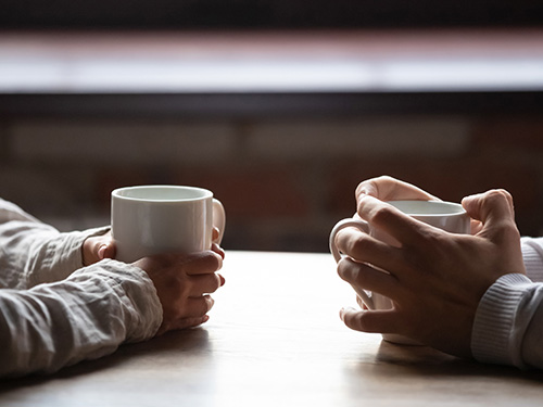 les mains de deux personnes avec deux tasses de café